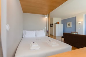 A hotel room with a bed, a desk, a chair, and a wardrobe. - Liiiving in Porto - Lobo Studio II (Porto)