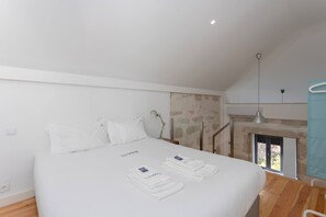 A bedroom with a large bed, a nightstand, a lamp, and a view of the outdoors. - Liiiving in Porto - Design Loft Marqu s (Porto)