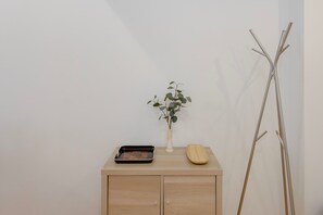 A wooden cabinet with a tray, a vase with a plant, and a wooden coat rack. - Liiiving in Porto - Design Loft Marqu s (Porto)