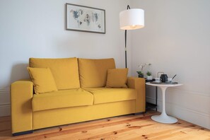 A yellow sofa with a white floor lamp and a small table with a teapot and cups. - Downtown Balcony Studio II (Porto)