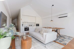 Ein stilvolles Wohnzimmer mit einem weißen Sofa, einem Holztisch und einem Esstisch mit Stühlen.