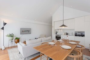 A modern living space with a dining area, a sofa, a coffee table, and a kitchen in the background. - Liiiving in Porto - The Prestige Apartment K (Porto)