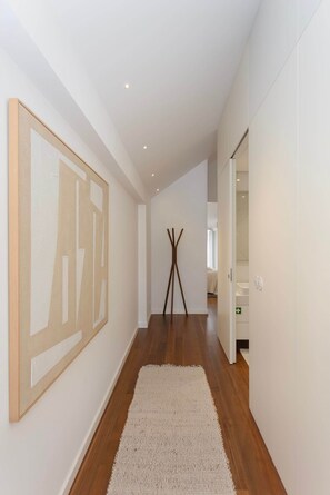 Ein Flur mit Holzboden, einem weißen Teppich und einem großen abstrakten Gemälde an der Wand.