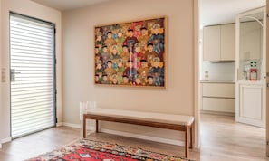 A room with a bench, a door with blinds, a wall-mounted painting, and a kitchen area. - Liiiving in Porto - Foz Garden House 3 bdr (Porto)