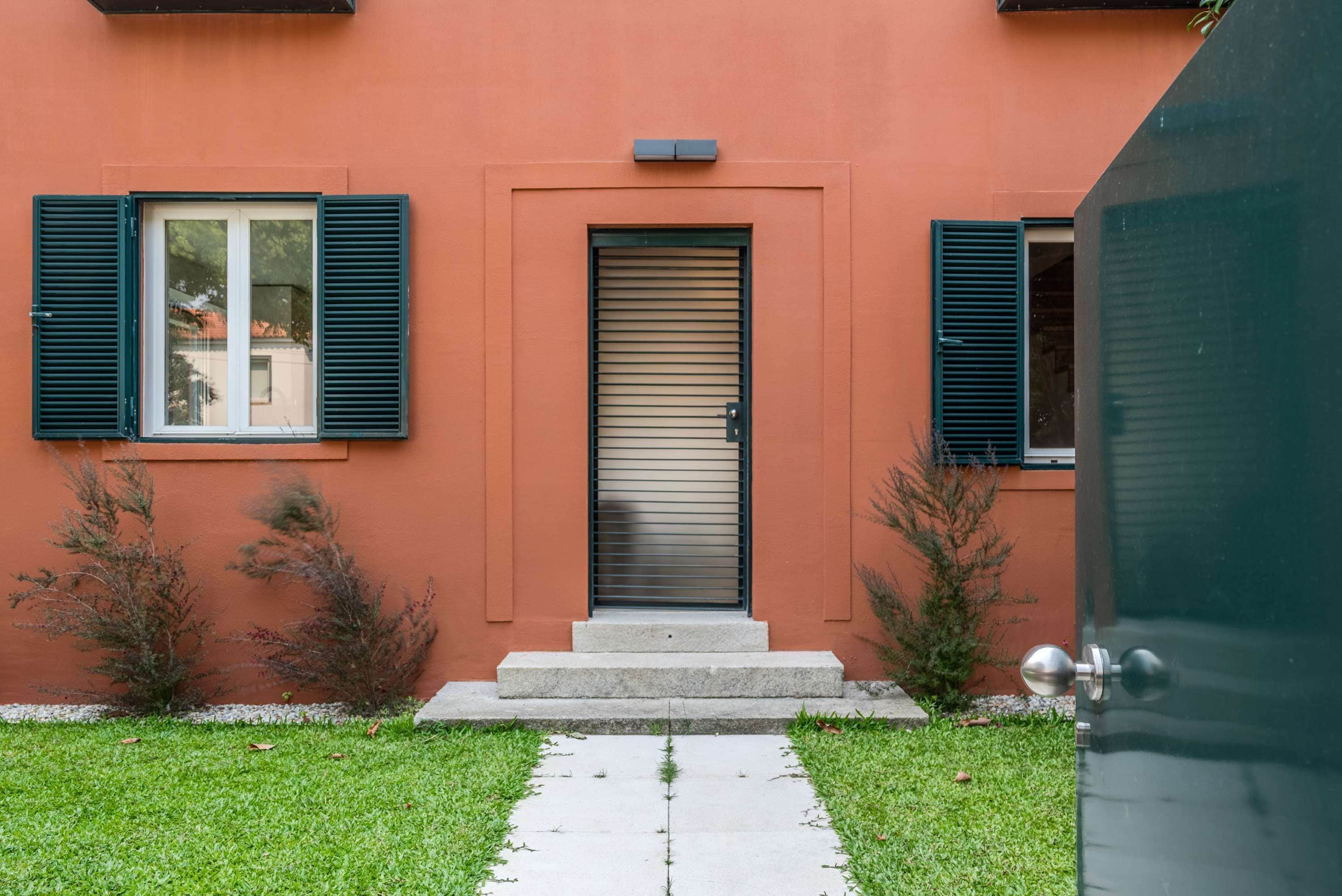 A building with a red facade, a sliding door, and a small set of steps leading to the entrance.