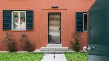 A building with a red facade, a sliding door, and a small set of steps leading to the entrance.