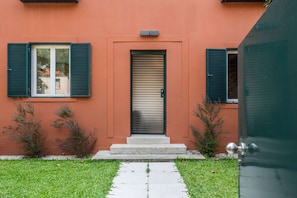 A building with a red facade, a sliding door, and a small set of steps leading to the entrance. - Liiiving in Porto - Foz Garden House 3 bdr (Porto)