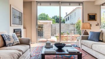 A living room with a sofa, a coffee table, and a view of a courtyard with outdoor furniture.