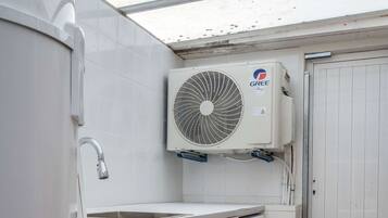 A compact laundry room with a washing machine, a dryer, and a ceiling-mounted air conditioning unit.