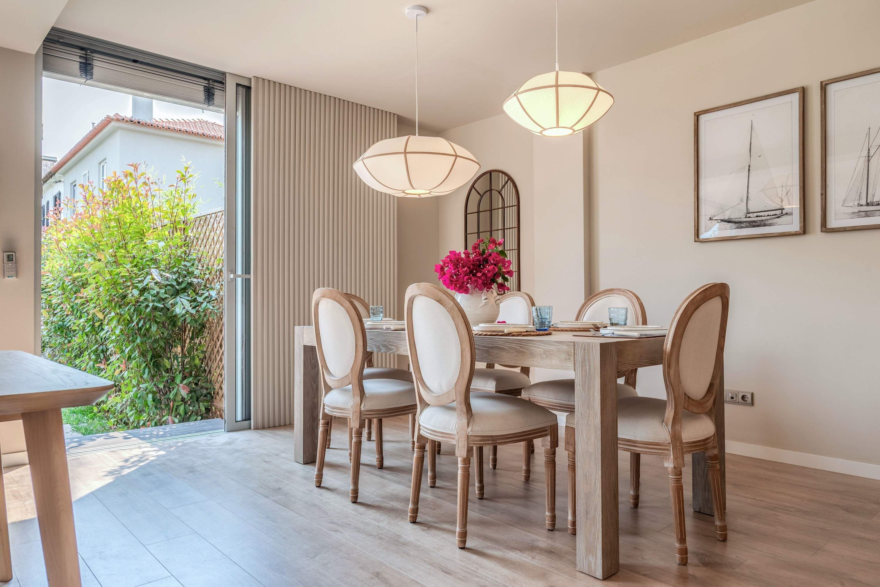 A dining area with a table set for four, surrounded by wooden chairs with cushioned seats.