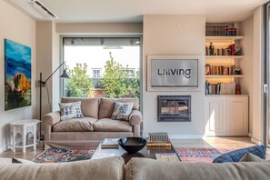 Un salon comprenant un canapé, une table basse, une cheminée et une bibliothèque.