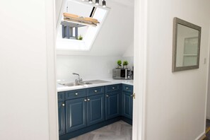 A kitchen with a skylight, a microwave, and a sink. - Tradewinds - 2 Bedroom Apartment - Tenby (Tenby)