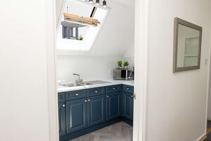 A kitchen with a skylight, a microwave, and a sink.