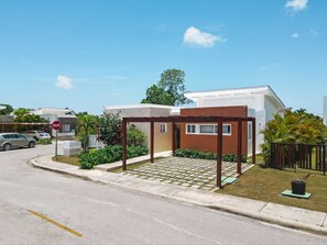 A residential area with a white house, a wooden pergola, and a stop sign. - Modern 3BR Villa With Private Pool in Oasis del Lago by Vistacana Rentals (Punta Cana)