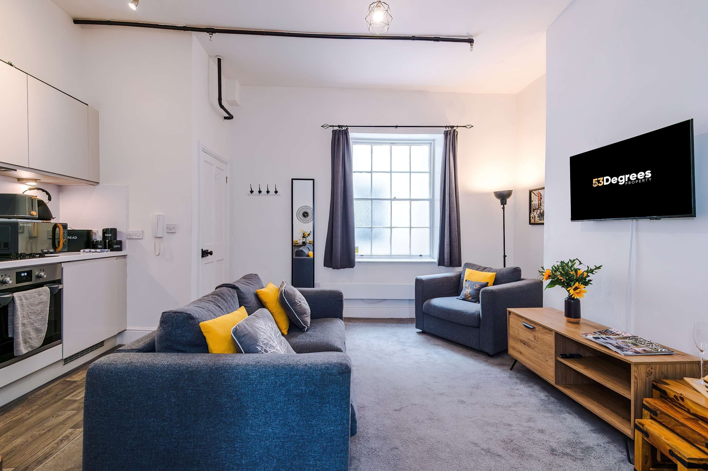 A modern living room with a sofa, armchairs, a TV, and a wooden sideboard.
