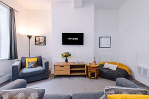 A modern living room with a sofa, a coffee table, a TV, and a small wooden cabinet. - Hideaway City Centre Flat in Chester Sleeps 2 (Chester)