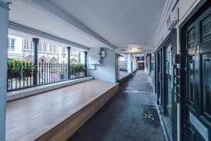 A corridor with a bench, a black door, and a building with a sign 'Inked Lip Chester'. - Hideaway City Centre Flat in Chester Sleeps 2 (Chester)