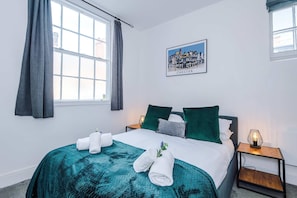 A hotel room with a large bed, a framed picture of Chester, and a window with curtains. - Hideaway City Centre Flat in Chester Sleeps 2 (Chester)