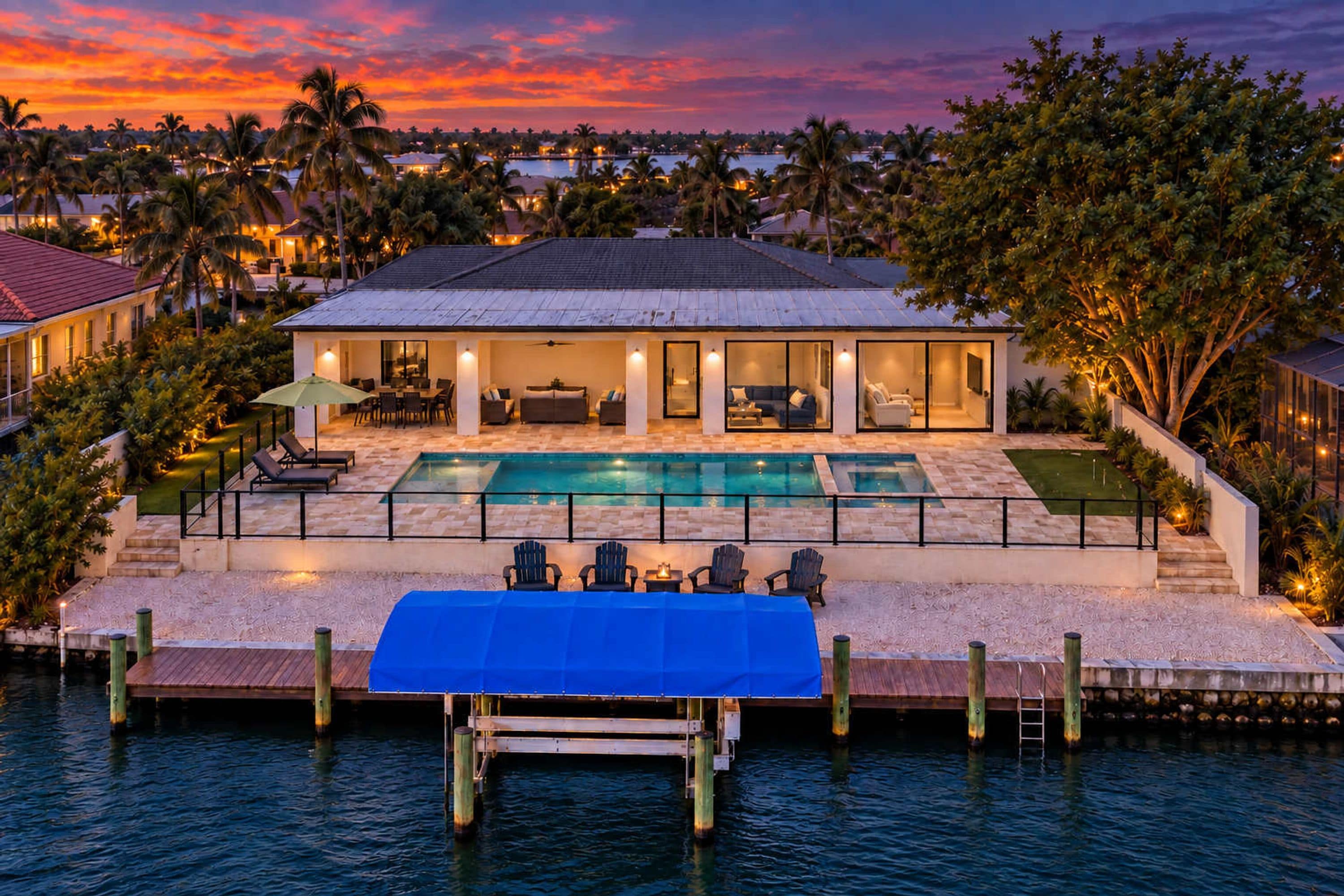 A waterfront property with a swimming pool, outdoor seating, and a dock extending into the water.