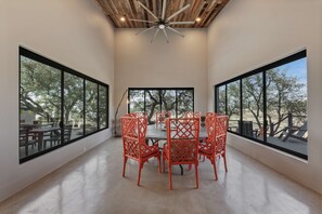 A room with a round table and chairs, large windows, and a ceiling fan. - Lake Buchanan Bliss Pool Spa Lakefront Beach (Burnet)