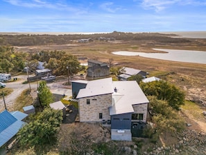 A residential area with multiple houses, a body of water in the background, and a clear sky. - Lake Buchanan Bliss Pool Spa Lakefront Beach (Burnet)
