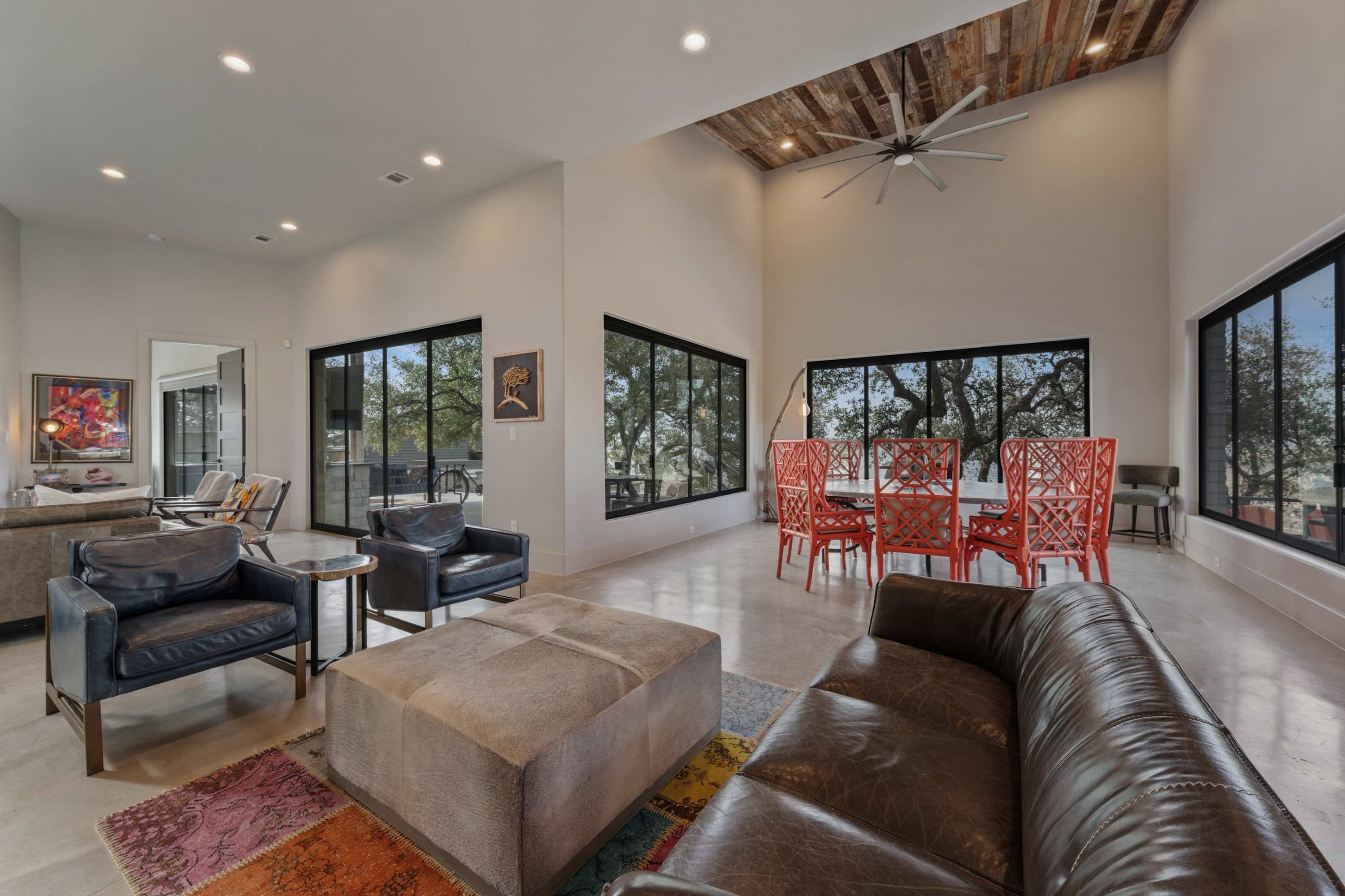 A spacious living room with a leather sofa, a coffee table, and a dining area with red chairs.