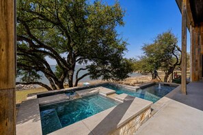 A swimming pool with clear water, surrounded by trees and a view of the sea. - Lake Buchanan Bliss Pool Spa Lakefront Beach (Burnet)