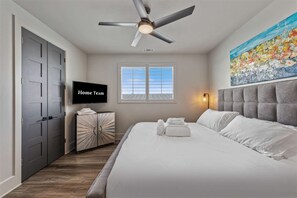 A hotel room with a bed, a television, a ceiling fan, a window, and a painting on the wall. - Lake Buchanan Bliss Pool Spa Lakefront Beach (Burnet)