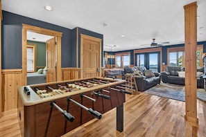 A room with a foosball table, a sofa, and a view of the outdoors. - Ski-out to Hatley Pointe Hot Tub Sleeps 8 (Mars Hill)
