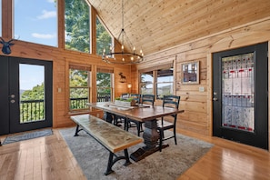 A wooden cabin interior with a dining table, benches, and a chandelier. - Ski-out to Hatley Pointe Hot Tub Sleeps 8 (Mars Hill)