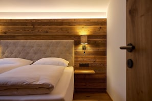 Een slaapkamer met een houten hoofdbord, een bedlampje en een deur.
