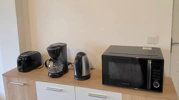 A kitchen area with a microwave, toaster, and coffee maker on a wooden cabinet.