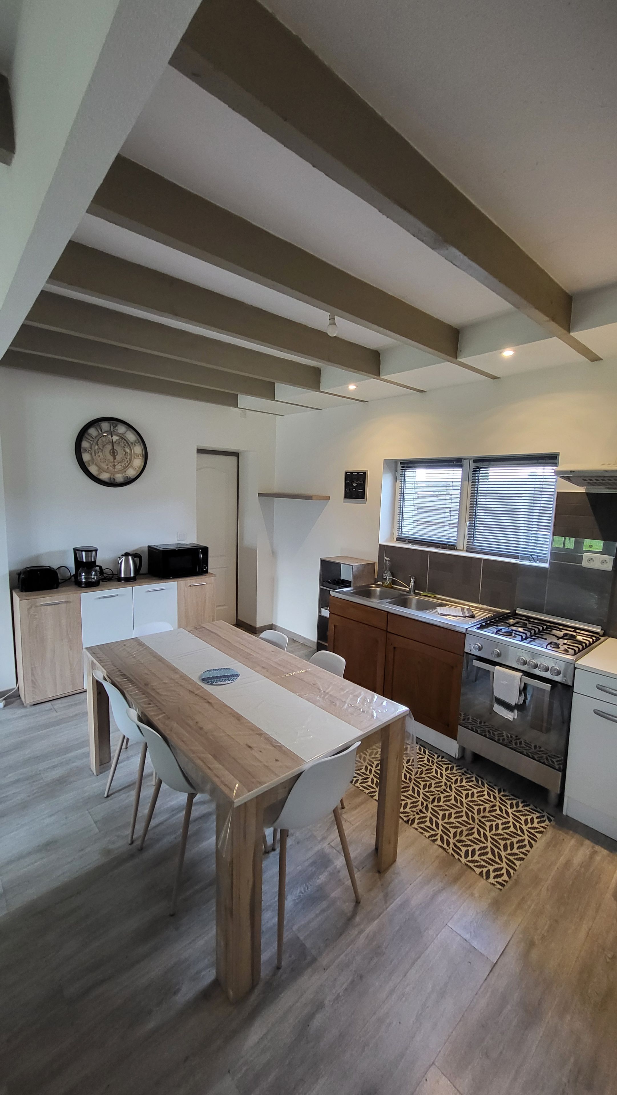Una cocina moderna con estufa a gas, horno y ventana con persianas.