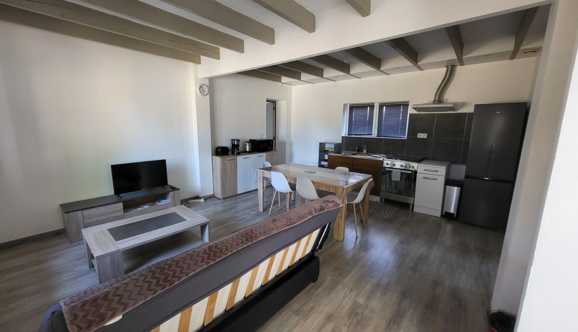 Une cuisine moderne avec un coin repas, un téléviseur et un canapé.