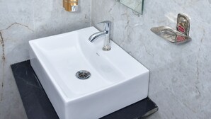 Un bagno con un lavandino bianco, uno specchio e un dispenser di sapone.