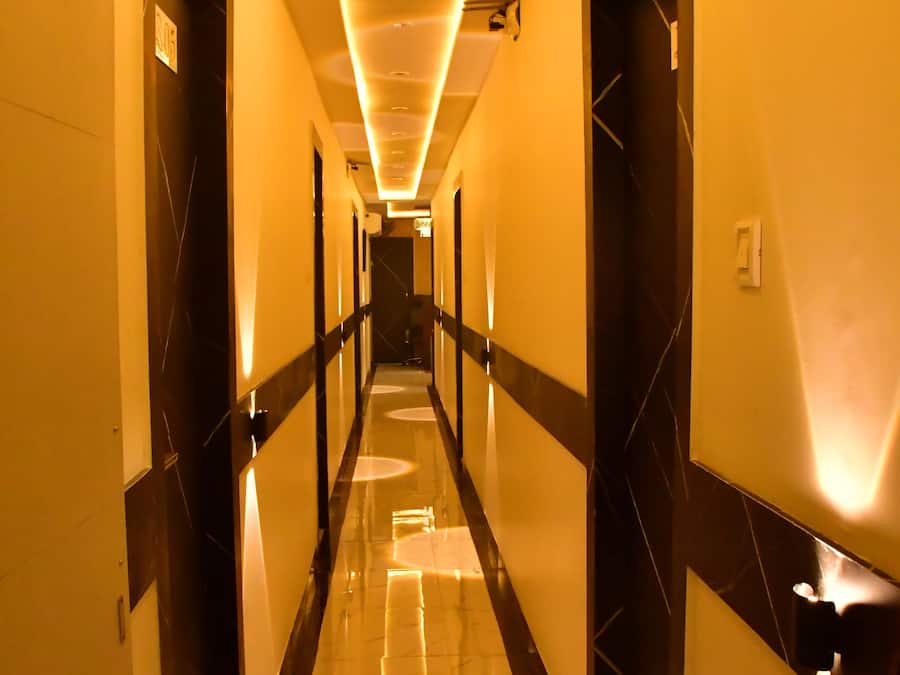 A hotel corridor with a reflective floor, doors on both sides, and overhead lighting.