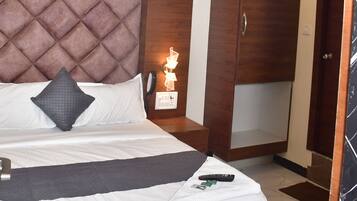 Une chambre d’hôtel équipée d’un lit, d’une armoire, d’un ventilateur de plafond et d’une lampe de chevet.
