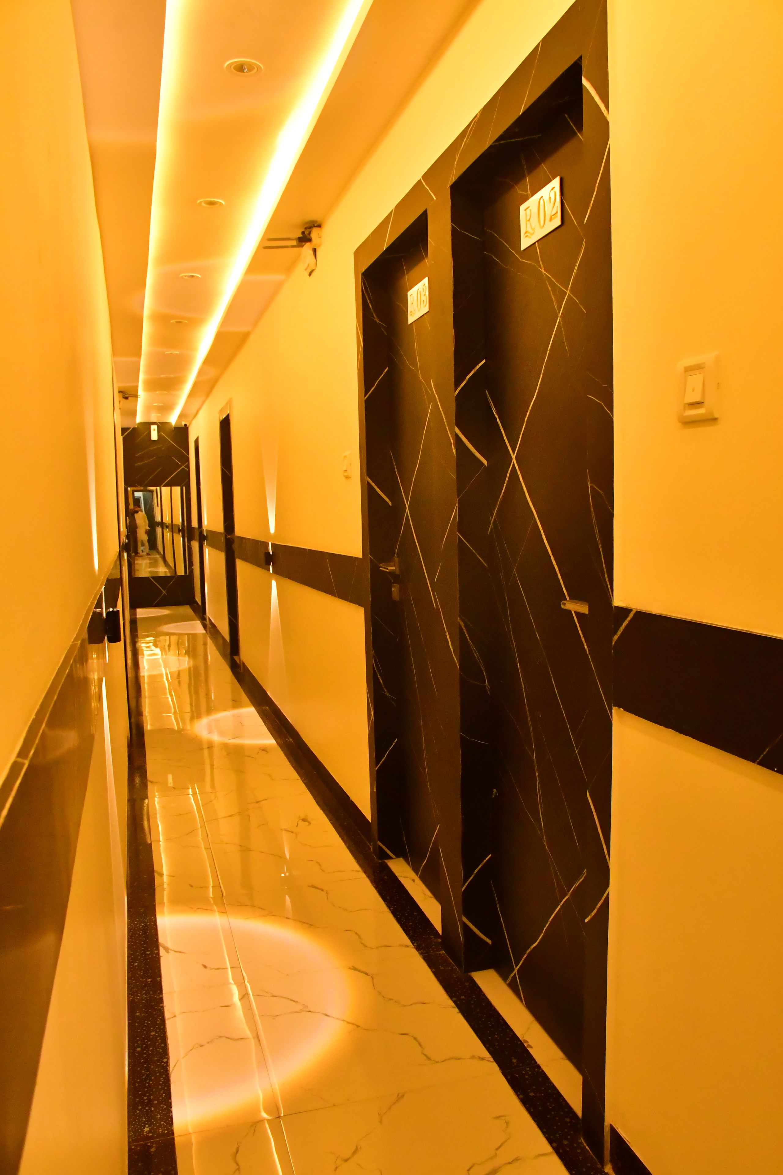 Pasillo de hotel con paredes de mármol negro, puertas numeradas y suelo brillante.