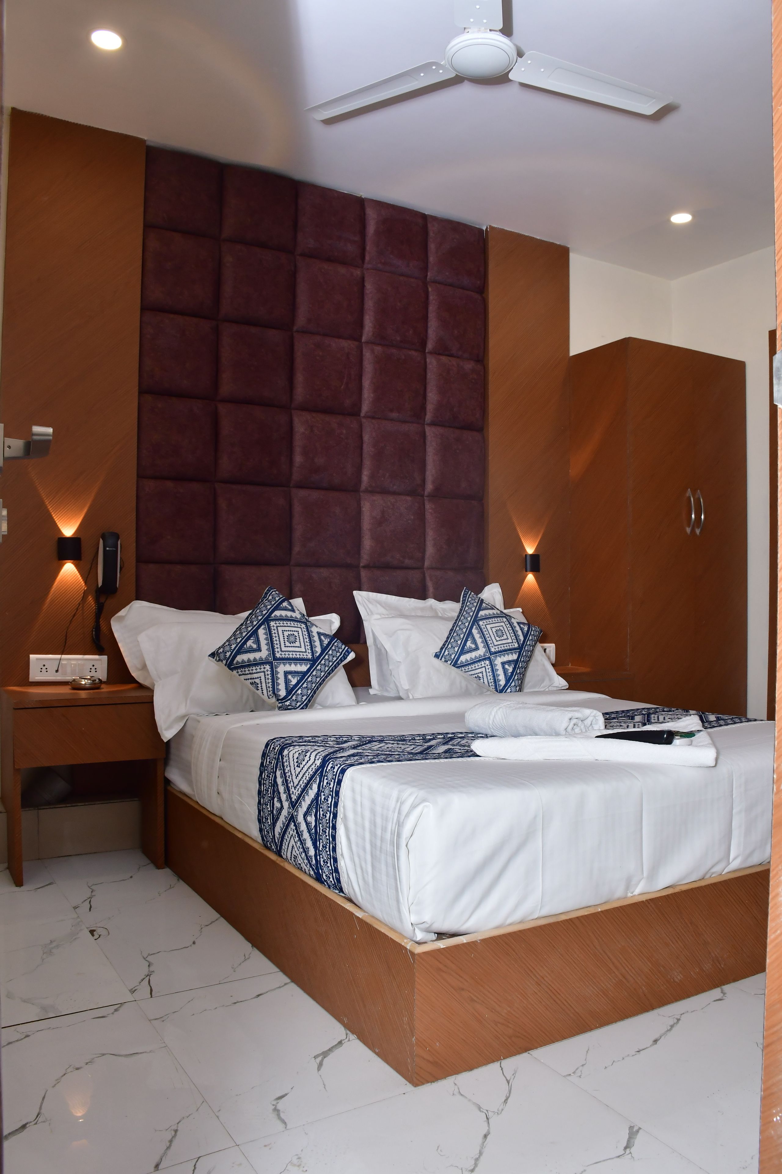 A hotel room with a bed, nightstands, a wardrobe, and a ceiling fan.