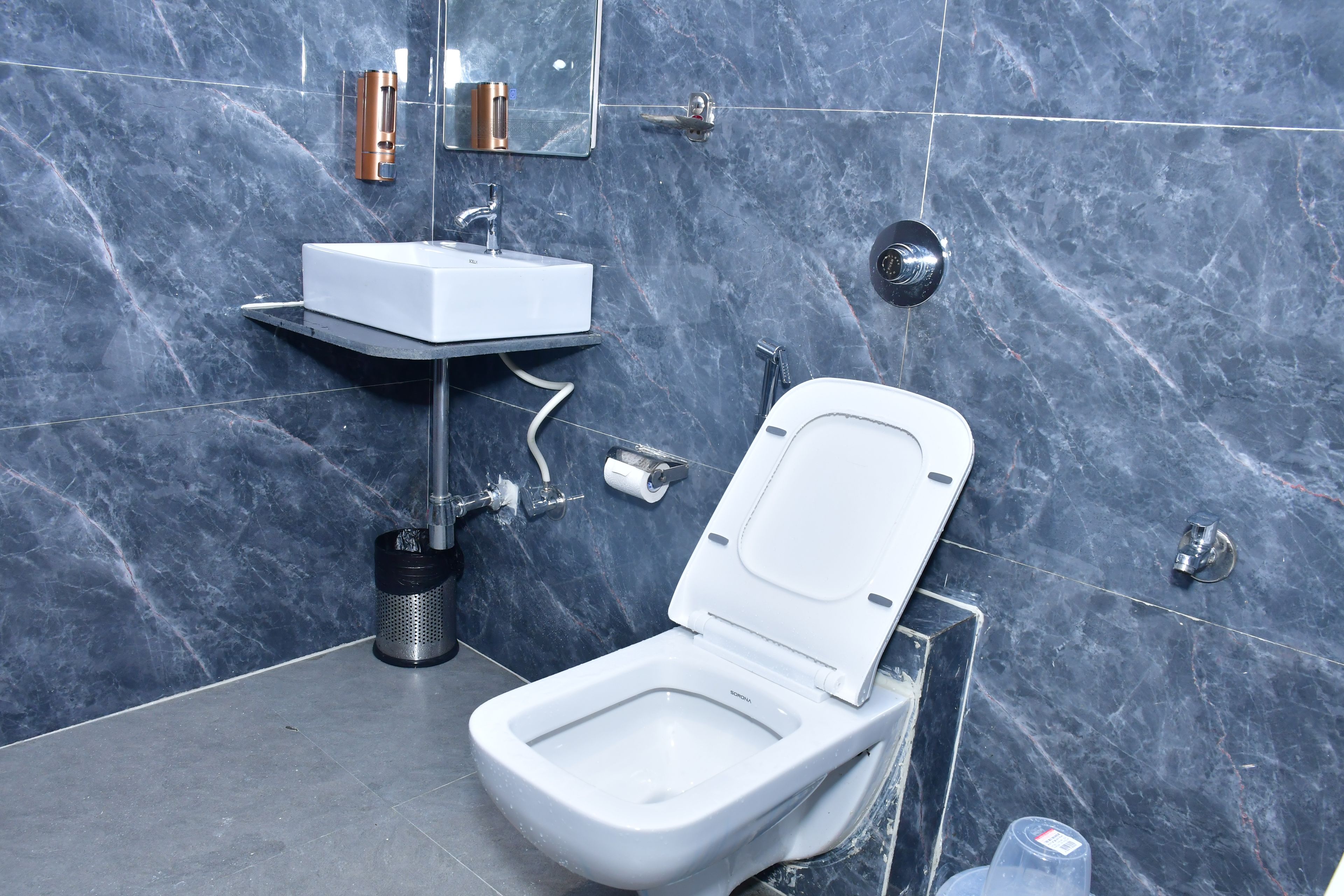 Un baño moderno con inodoro blanco, lavamanos y espejo.