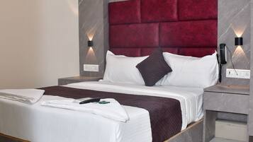 Une chambre d’hôtel moderne avec un grand lit, un sol en marbre et une tête de lit rouge recouverte de tissu.