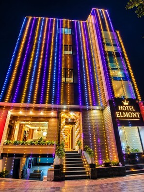 Un hotel con diseño moderno, destacando una entrada con escalera y un cartel que dice 'HOTEL ELMONT'.