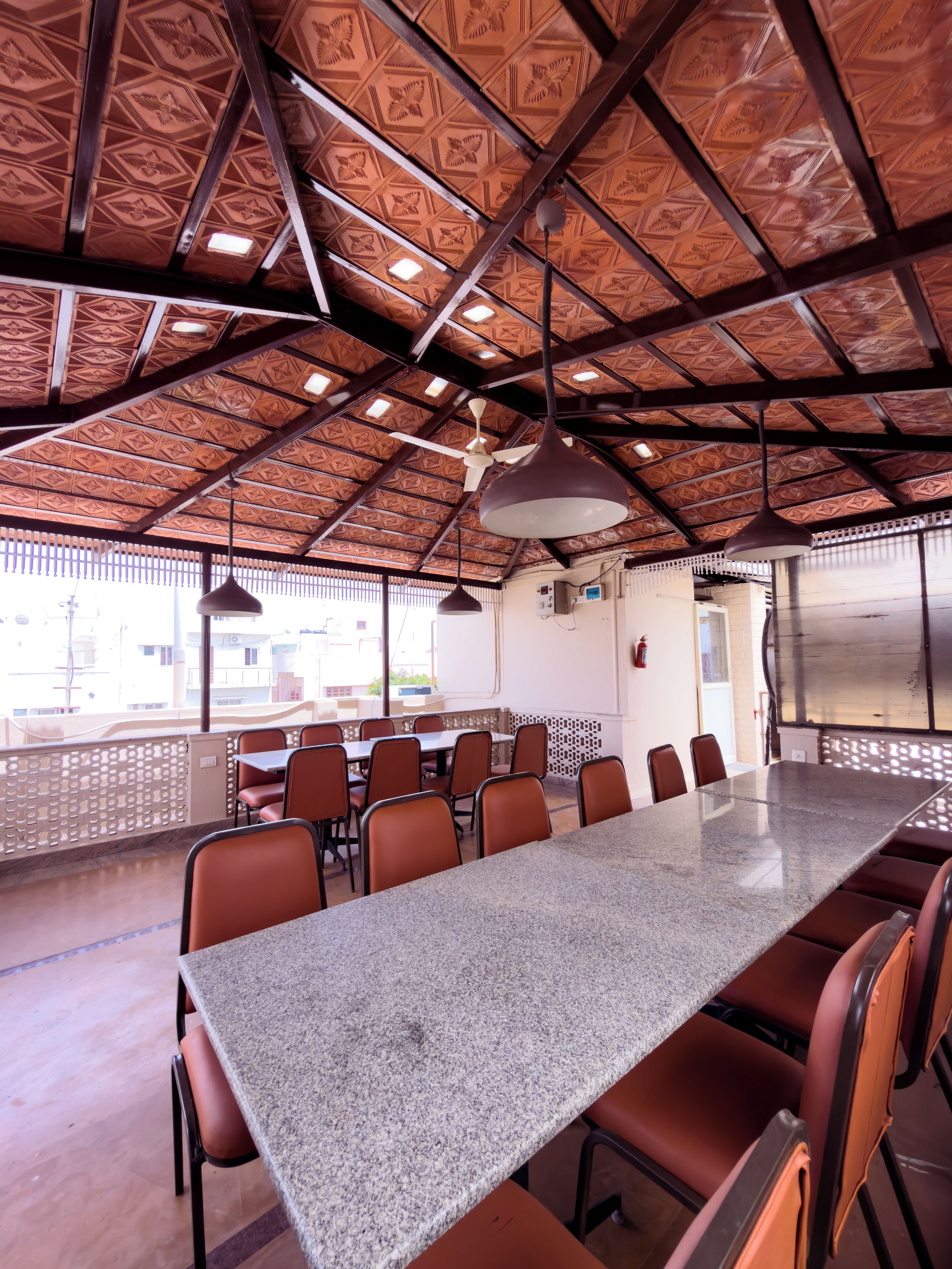 A conference room with a long table, multiple chairs, ceiling fans, and a patterned ceiling.