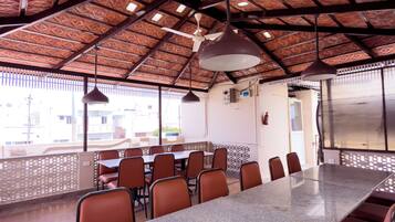 A conference room with a long table, multiple chairs, ceiling fans, and a patterned ceiling.
