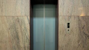 An elevator with a metallic finish, set in a wall with a textured surface.