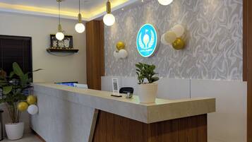 Un mostrador de recepción de hotel con diseño moderno, que incluye un suelo de mármol y detalles de madera.