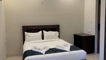 Una habitación de hotel con una cama grande, una mesita de noche y un velador.