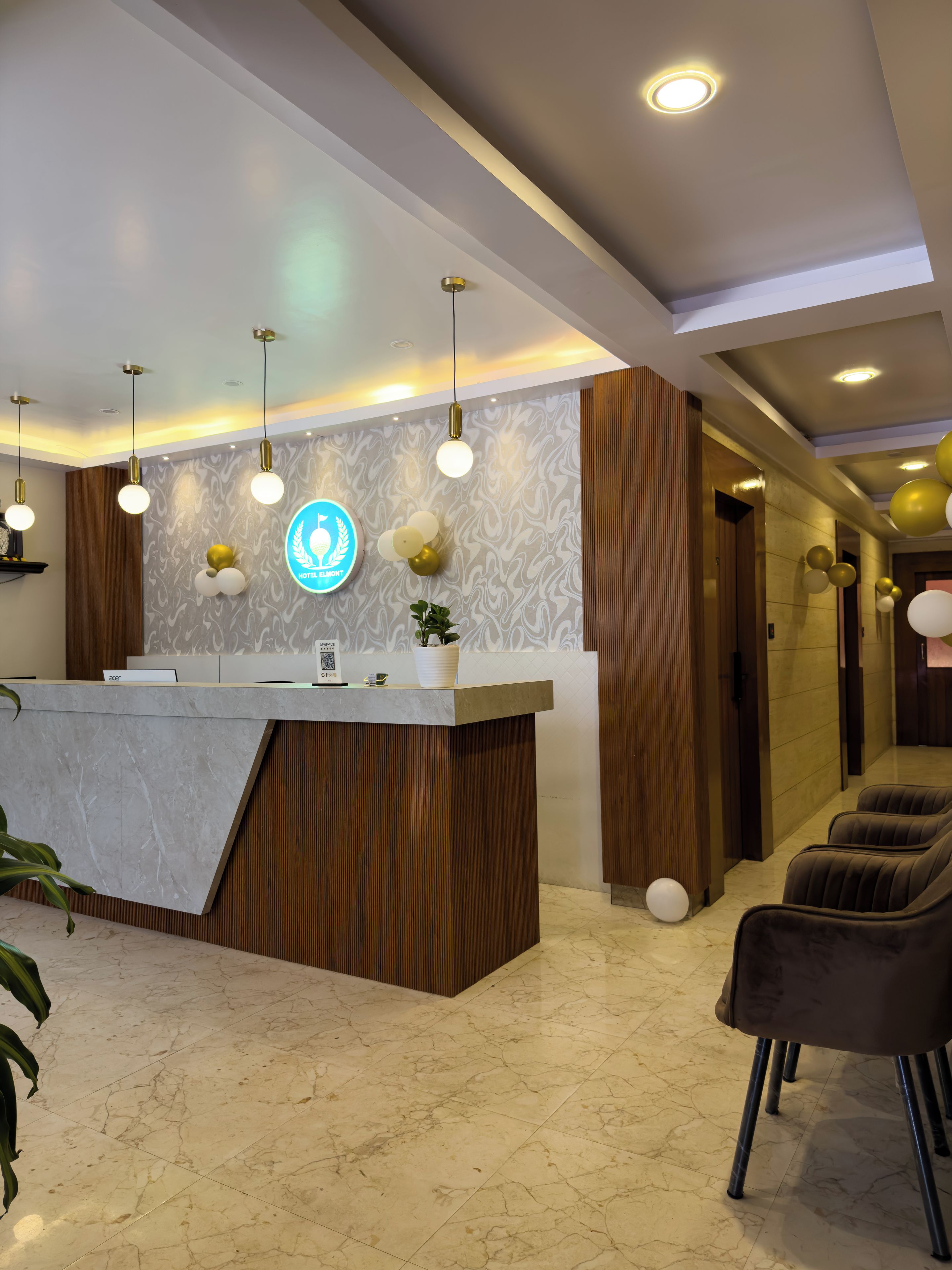 Zona de recepción de un hotel con suelo de mármol, un mostrador de recepción y un área de estar con sillas.