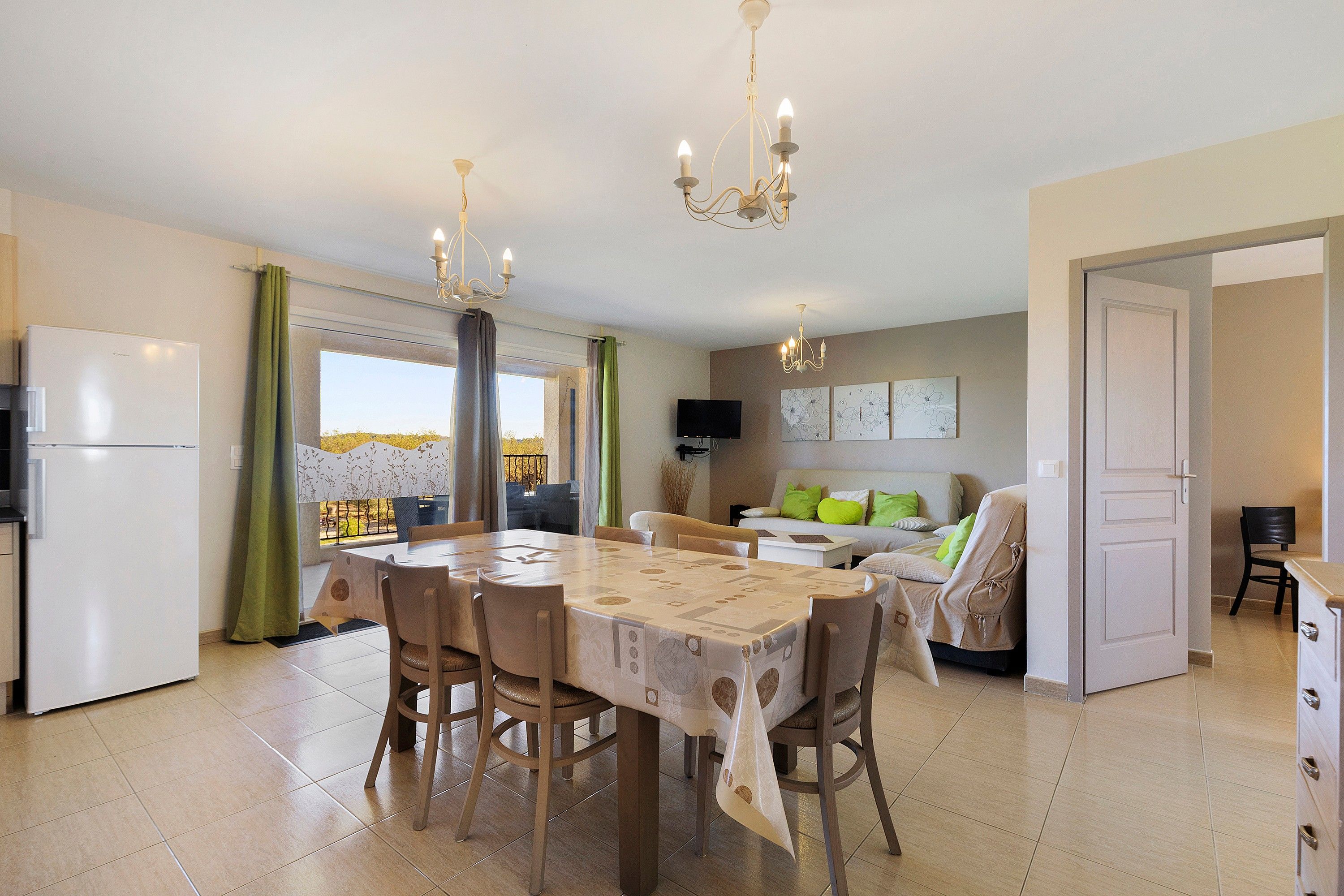 A modern kitchen with a dining table, chairs, and a refrigerator.