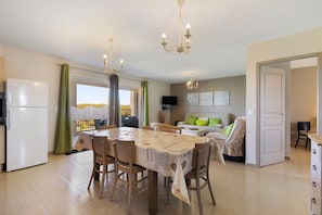 A modern kitchen with a dining table, chairs, and a refrigerator.